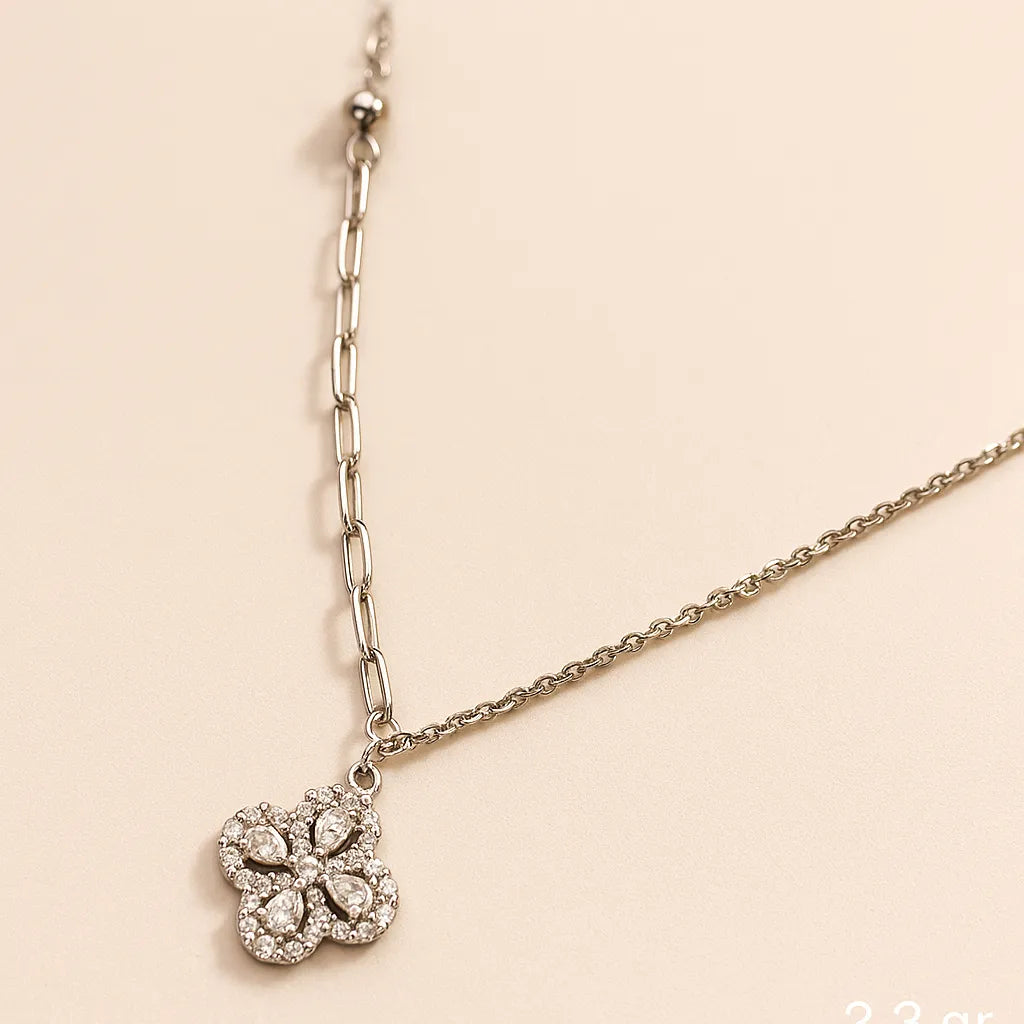 Silver necklace with a clover-shaped pendant on a beige background
