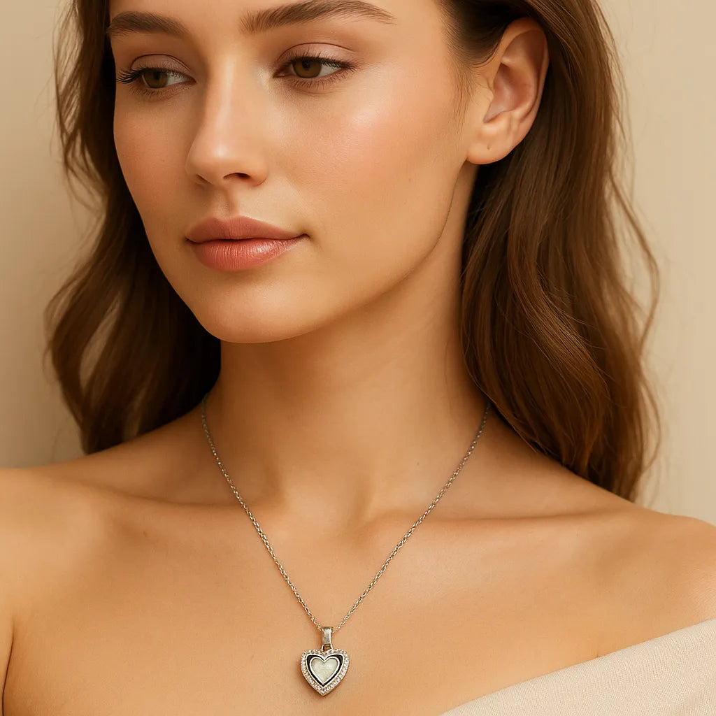 Woman wearing a silver necklace with a heart pendant against a neutral background