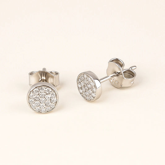 Silver stud earrings with clear gemstones on a light beige background