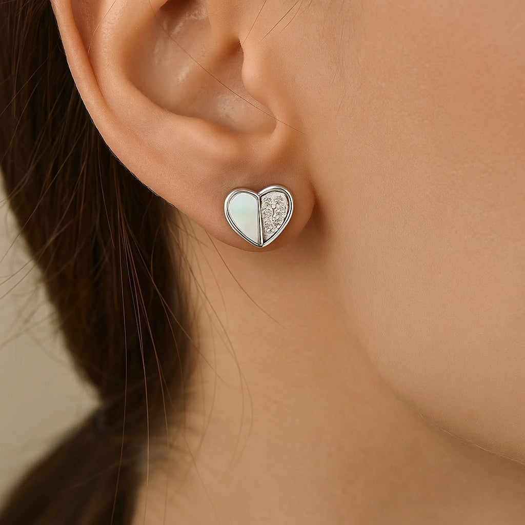 Heart-shaped earring worn by a person with a neutral background