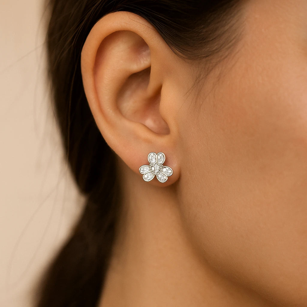 Flower-shaped earring worn on an ear with a neutral background