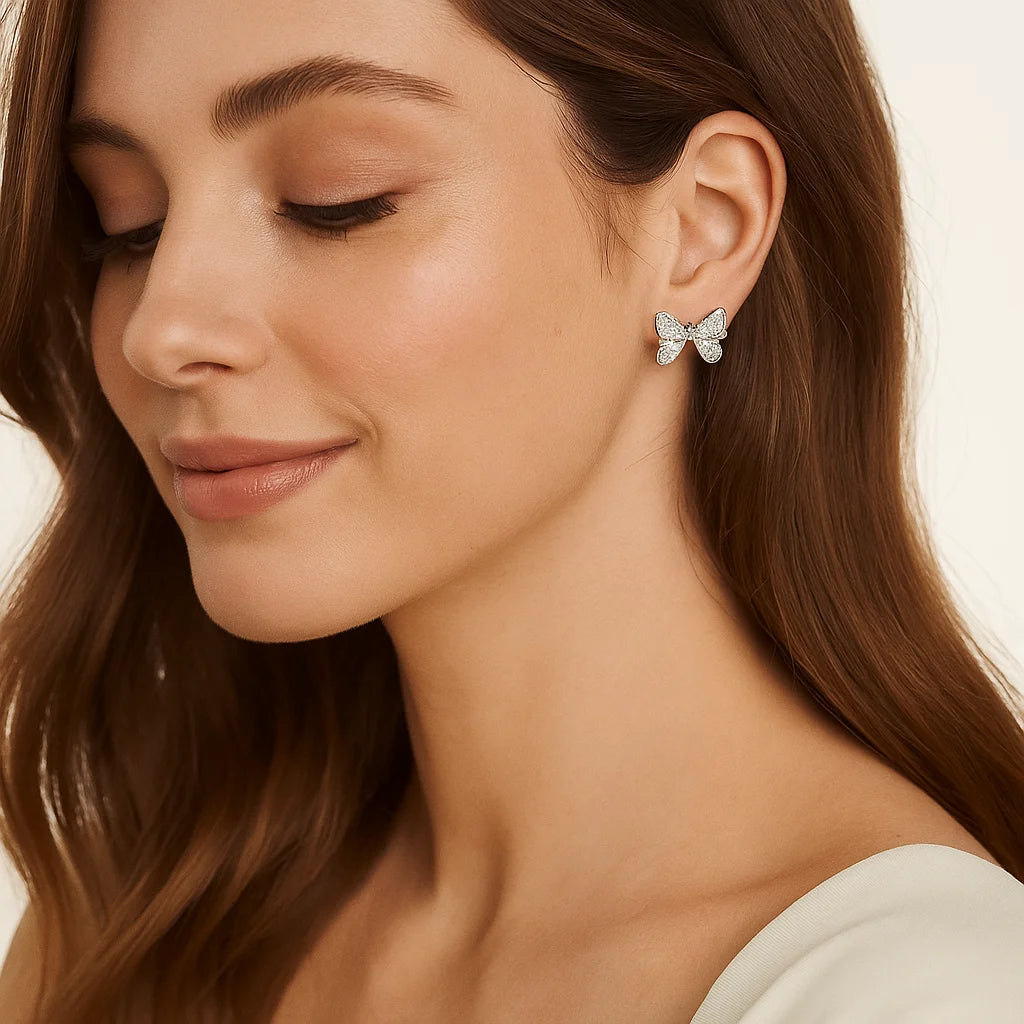 Close-up of a woman wearing butterfly earrings with a neutral background