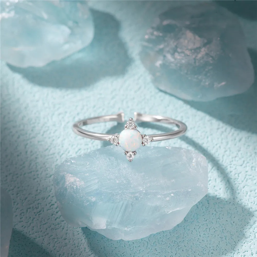 Silver ring with a central gemstone on a light blue textured surface