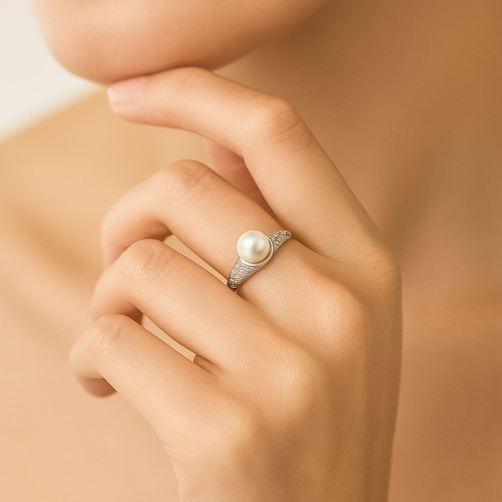 Pearl ring on a hand against a beige background