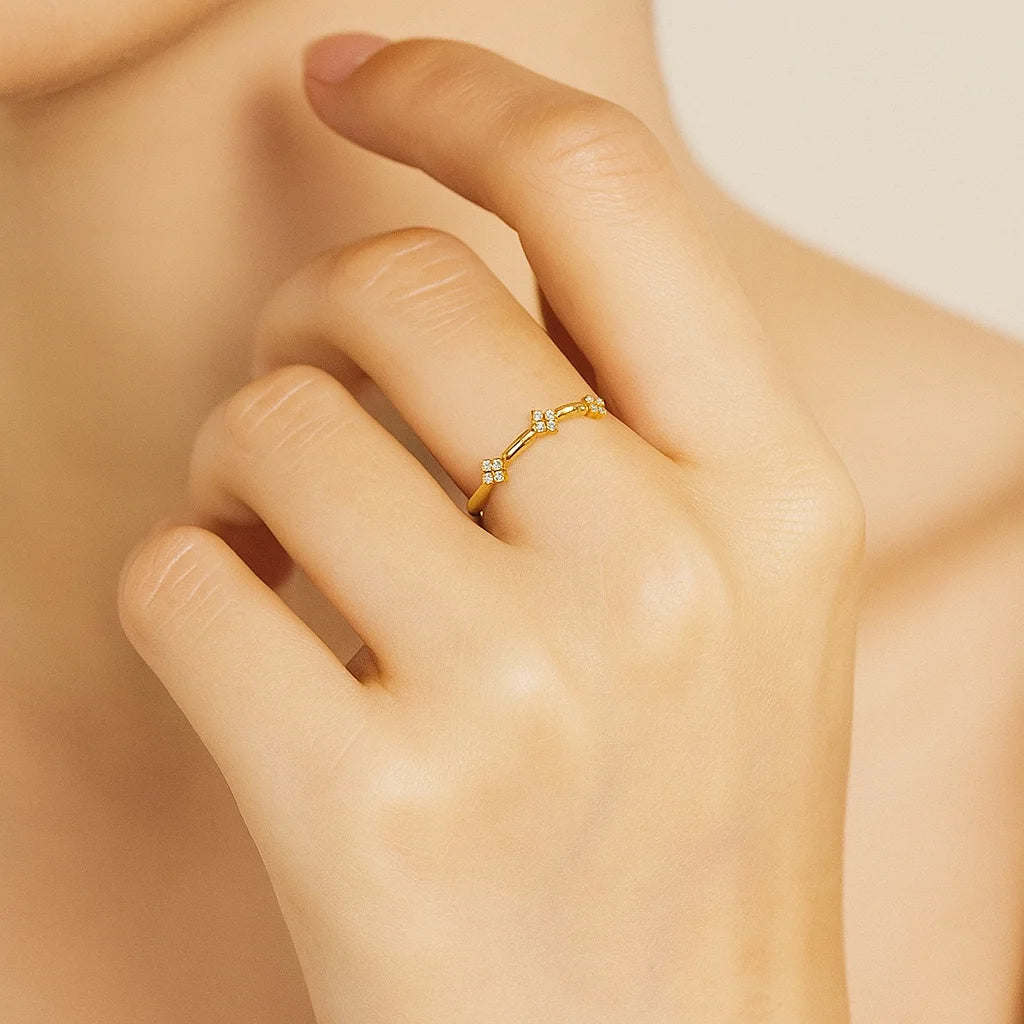Golden ring with small diamonds on a hand against a neutral background