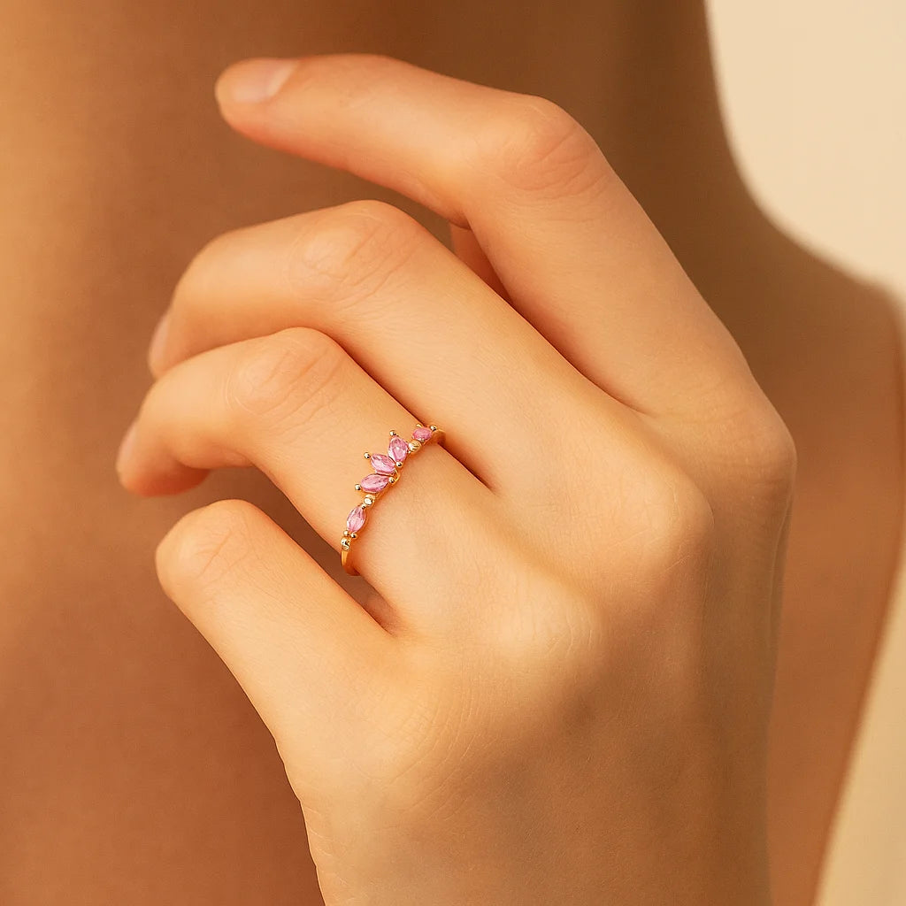 Hand wearing a pink gemstone ring against a warm beige background