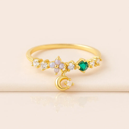 Golden ring with green gemstone and moon design on a beige background
