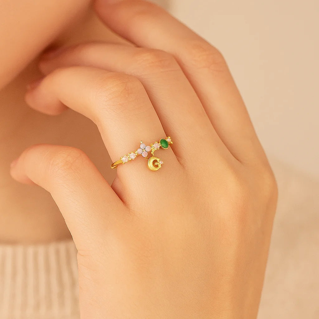 Golden ring with colorful stones on a hand against a beige background