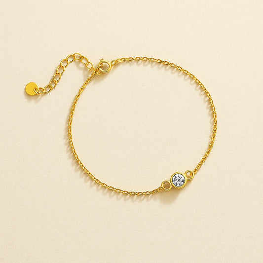 Golden bracelet with a small round gemstone on a beige background