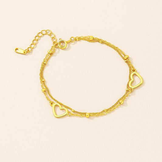 Golden bracelet with heart-shaped links on a beige background