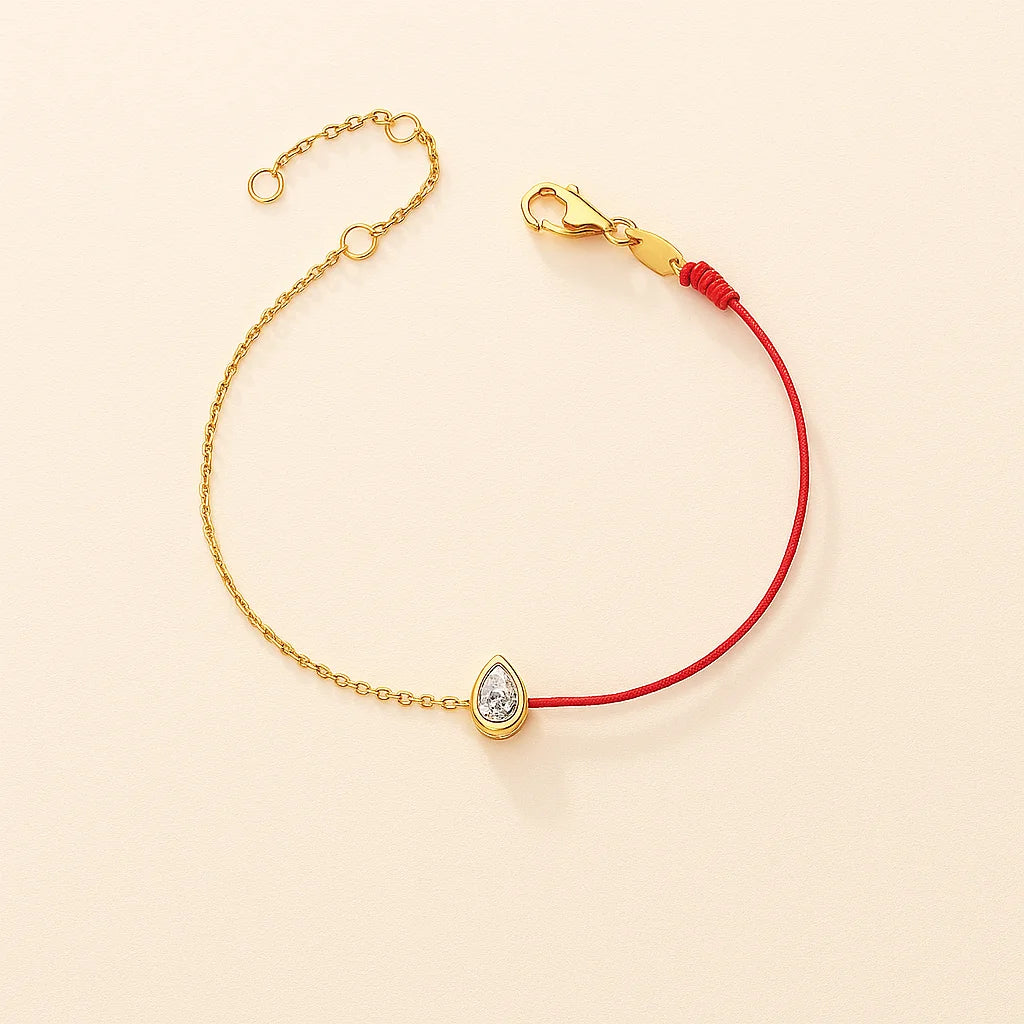Gold bracelet with a teardrop-shaped charm on a beige background