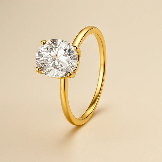 Gold ring with a clear gemstone on a beige background