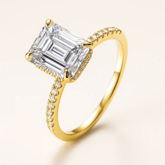 Gold ring with a large emerald-cut diamond and smaller diamonds on the band against a light background