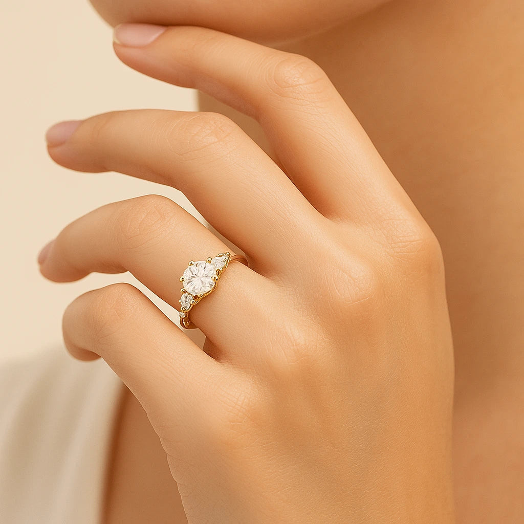 Gold plated ring with a diamond on a hand against a beige background