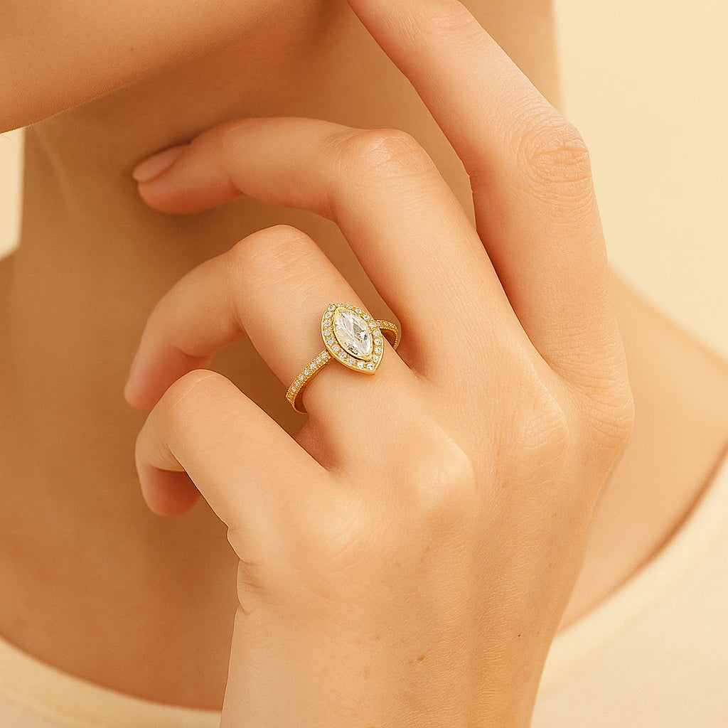 Close-up of a hand wearing a gold plated ring with a diamond on a neutral background