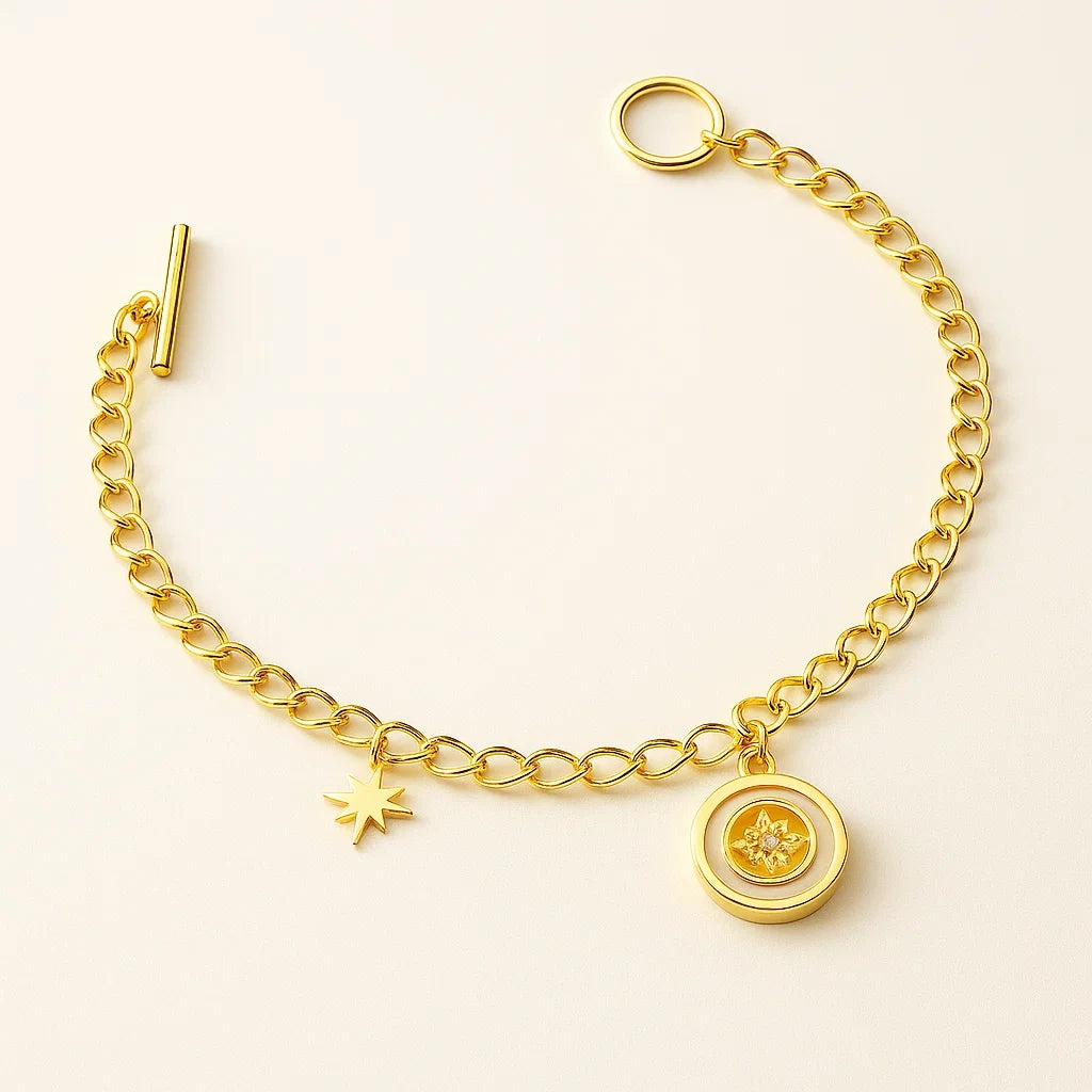 A gold-plated 925 sterling silver chain bracelet with a toggle clasp, featuring a small star charm and a round white enamel charm with a star design.