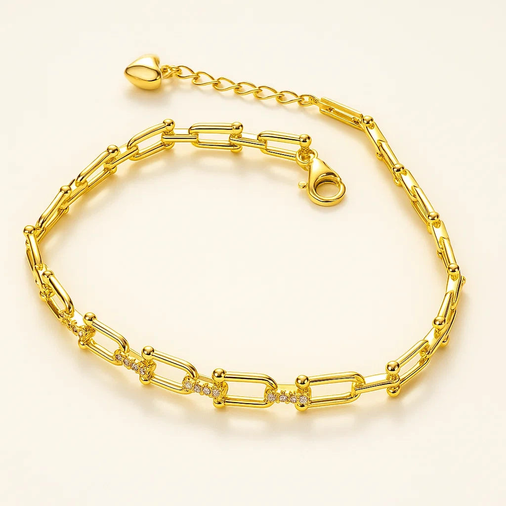 A gold-plated 925 sterling silver paperclip link bracelet with pave-set cubic zirconia stones on the center links and a heart charm on the extender.