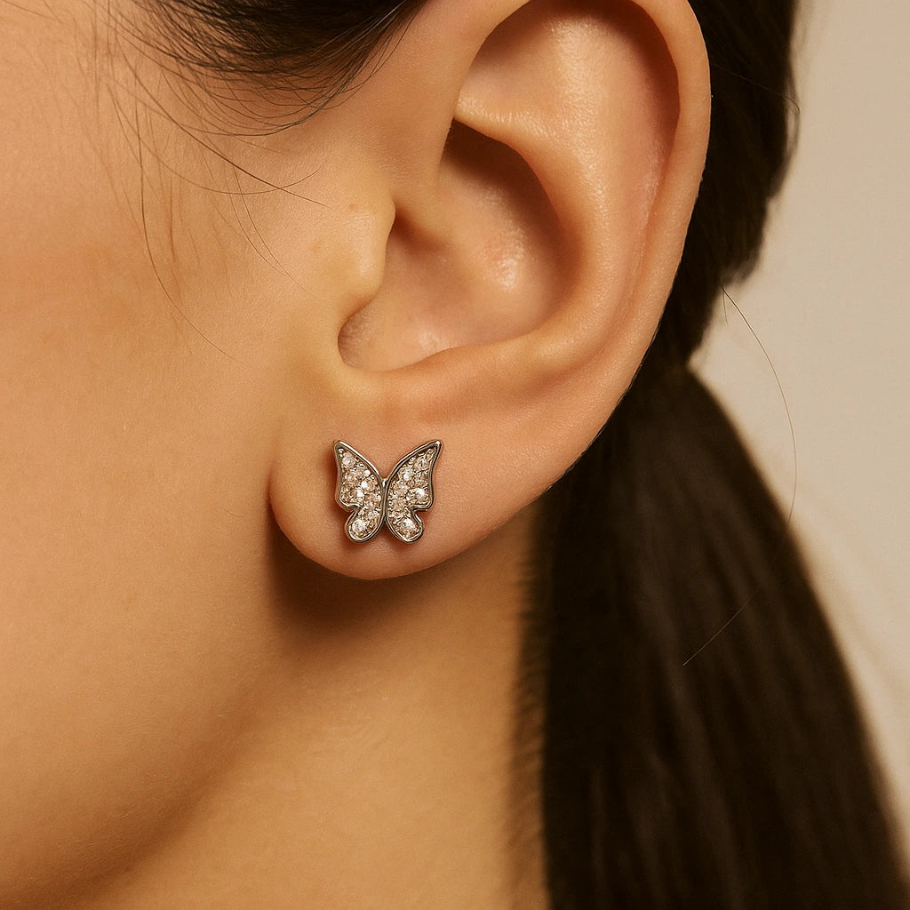 Butterfly-shaped earring worn on an ear with a neutral background
