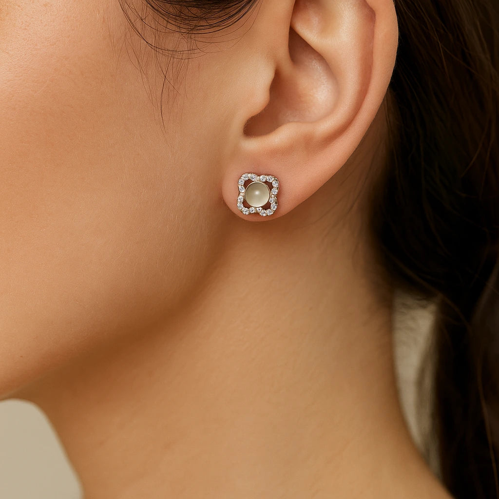 Close-up of an ear wearing a floral earring with a central gemstone.