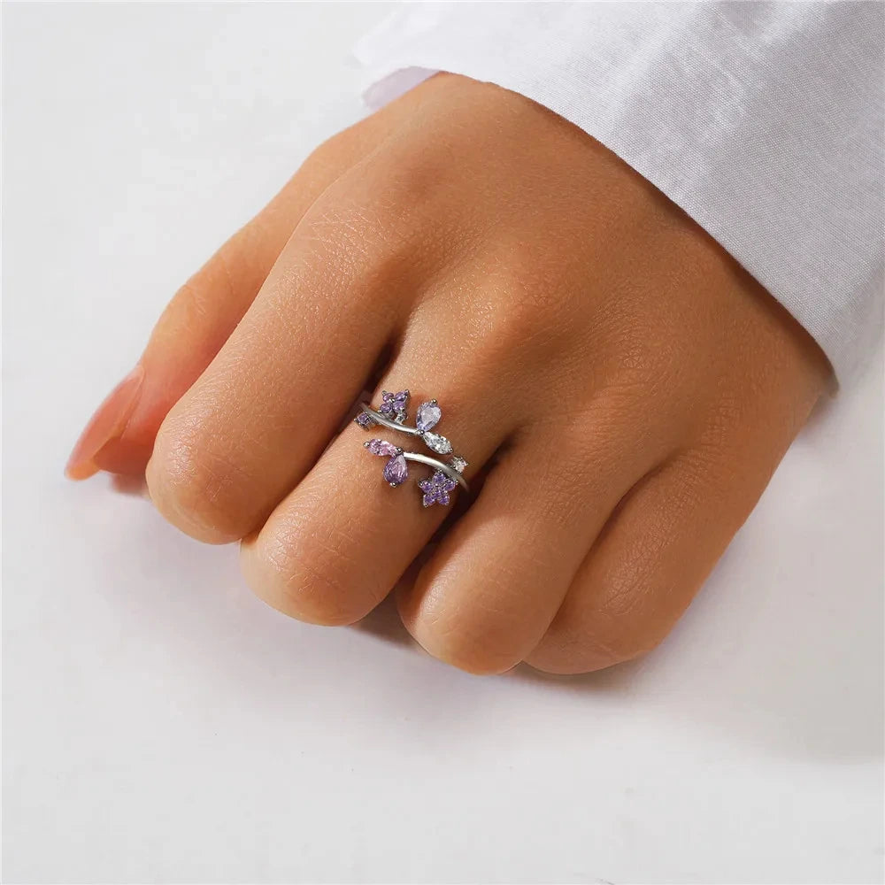 Hand wearing a silver ring with purple gemstones on a white background