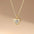 Gold heart-shaped necklace with a clear gemstone on a beige background