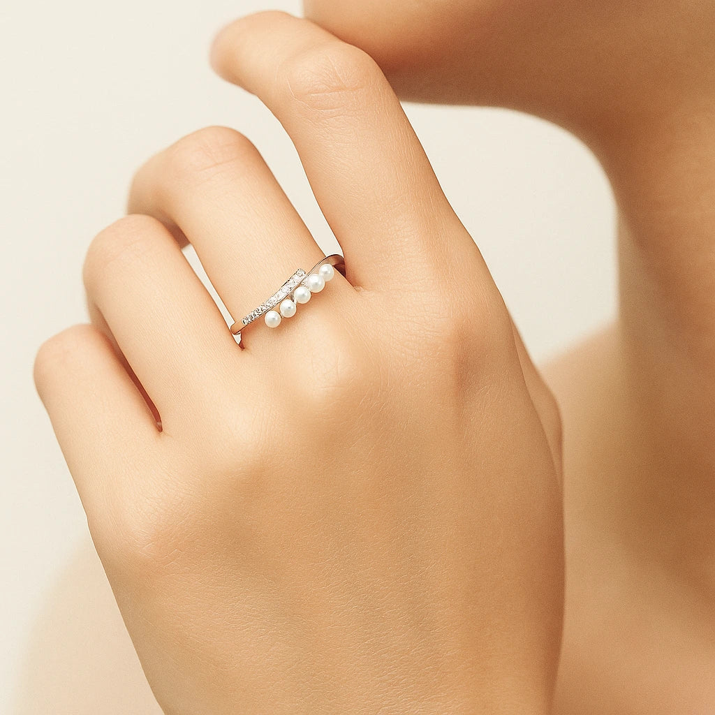 Pearl ring on a hand against a neutral background