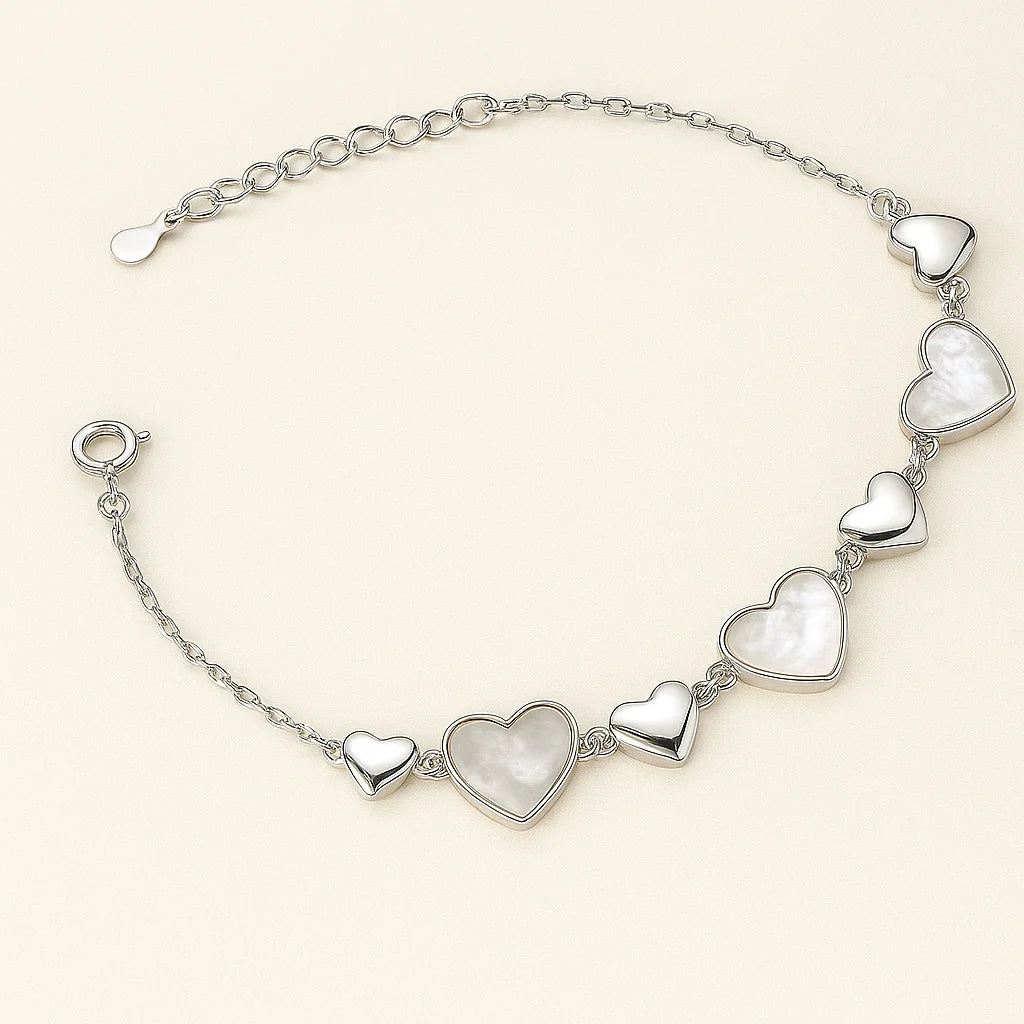A beautiful gold-plated sterling silver bracelet with a series of polished and mother-of-pearl inlaid heart charms.
