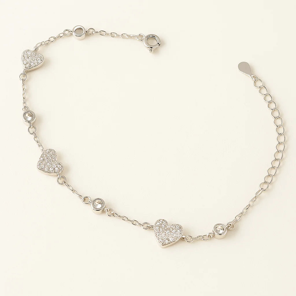 A beautiful gold-plated sterling silver bracelet featuring multiple pavé heart charms and single cubic zirconia accents.