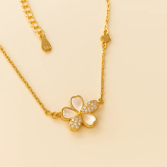 A delicate gold-plated sterling silver necklace with a flower pendant featuring mother-of-pearl and cubic zirconia details.