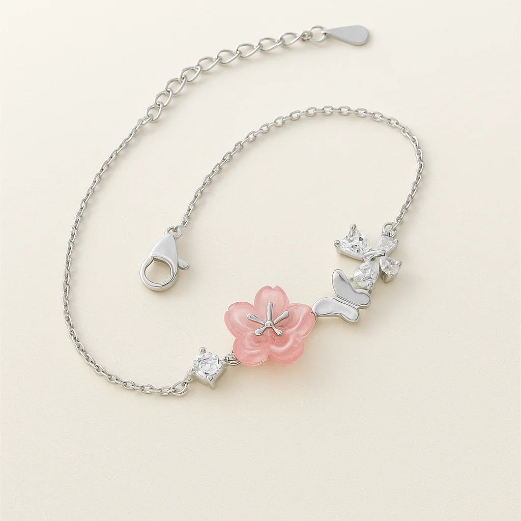Bracelet with pink flower and silver butterfly charms on a light beige background