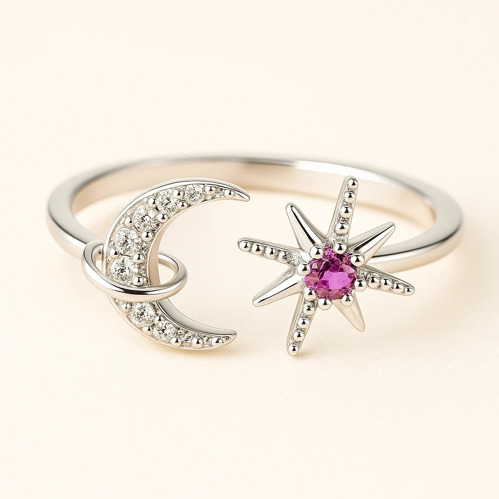 Silver ring with moon and star designs on a light background