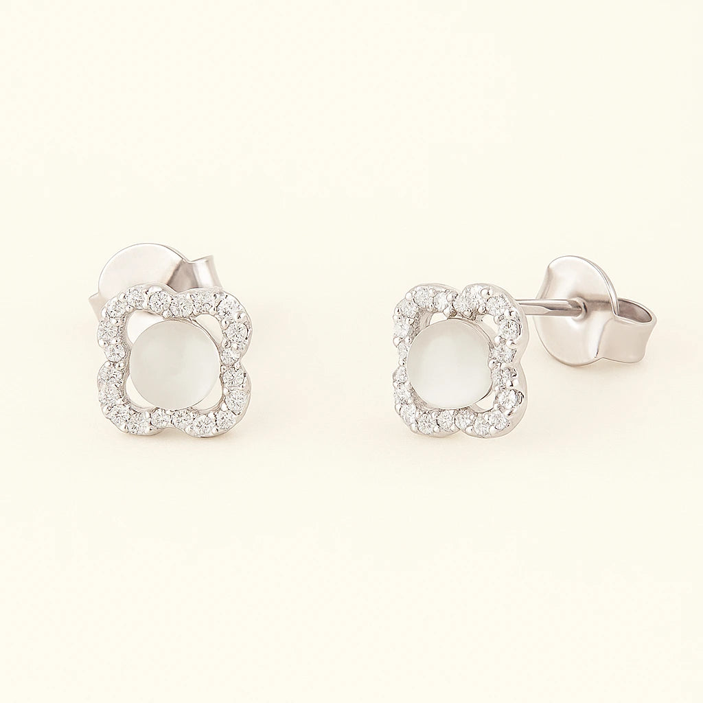 Silver earrings with white stones on a light beige background
