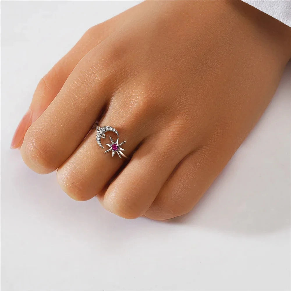 Silver ring with a red gemstone on a finger against a white background