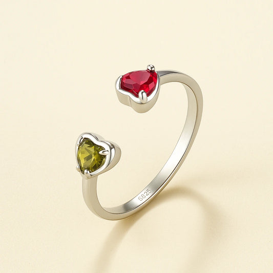 Silver ring with heart-shaped gemstones on a beige background