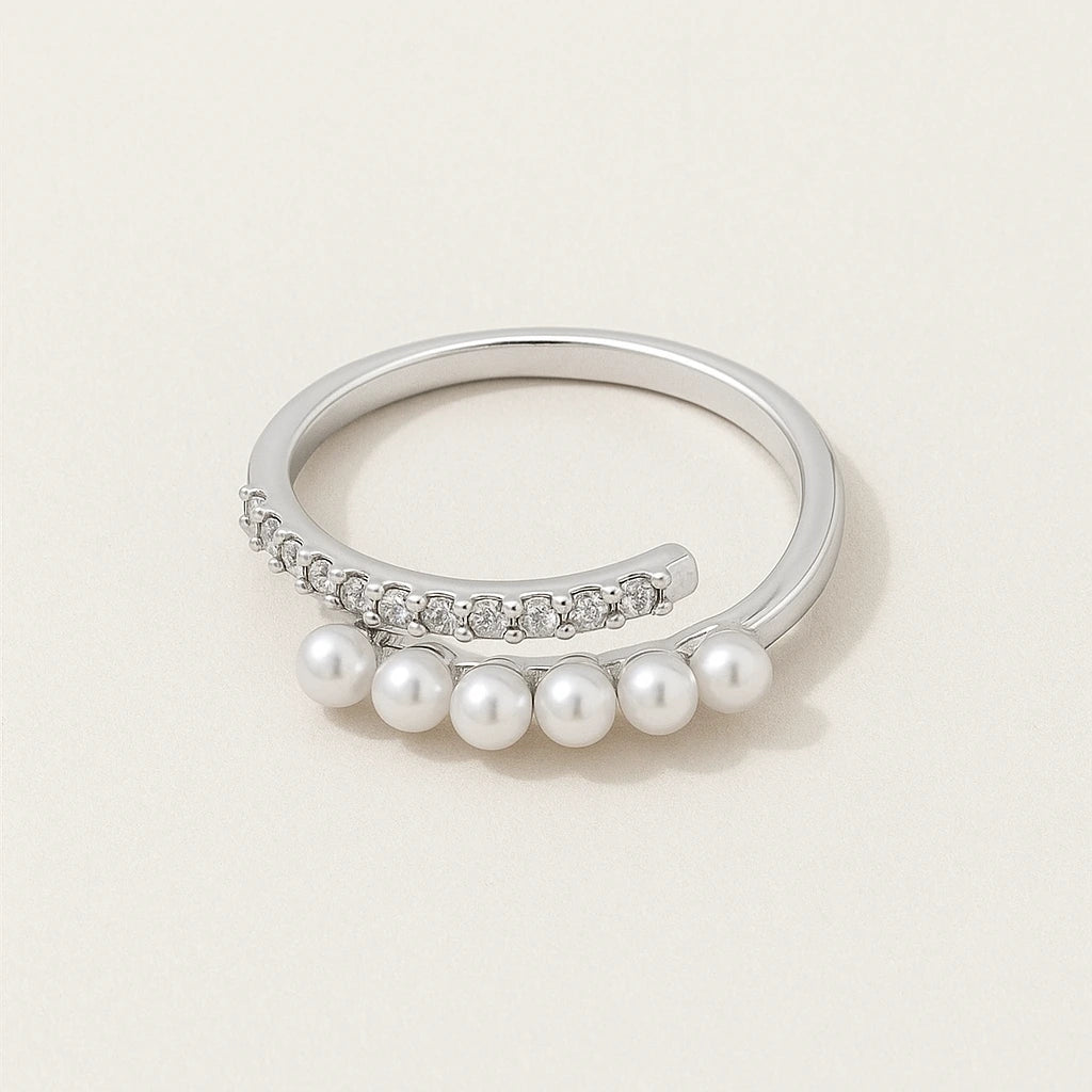 Silver ring with pearls and small diamonds on a light beige background