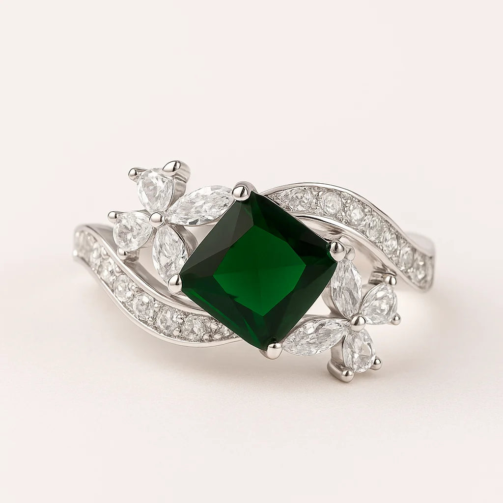 A 925 sterling silver ring with a central square green stone and a twisting band with floral clusters and pavé cubic zirconia.