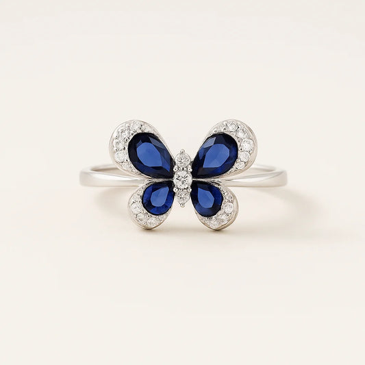 A 925 sterling silver ring with a butterfly centerpiece, with wings of blue or green pear-cut stones and a halo of pavé cubic zirconia.