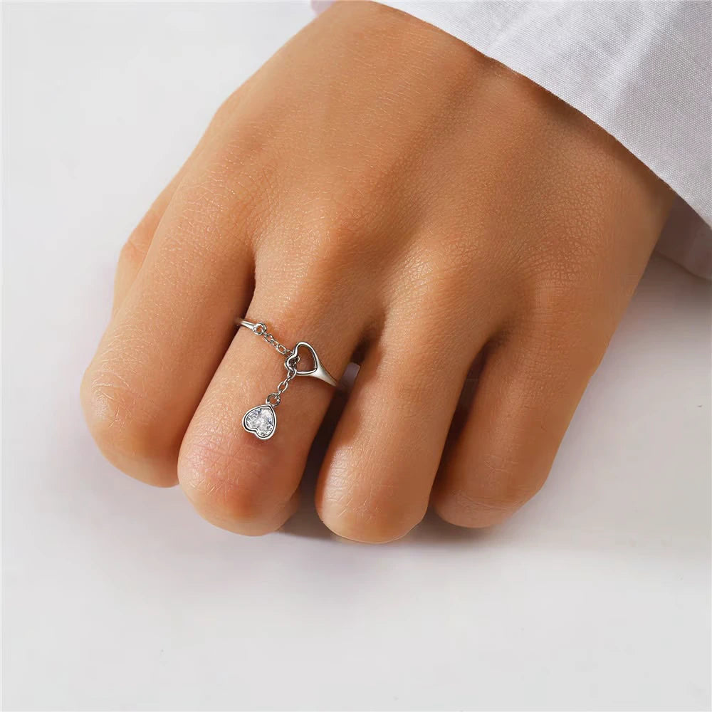 925 silver adjustable ring with two heart charms—one CZ-paved—connected by a fine dangling chain